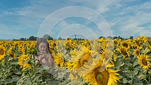 Teen looking at mobile phone while standing in a field surrounded by sunflowers