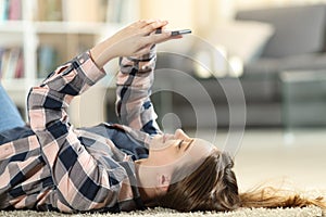 Teen lying on the floor using smart phone at home