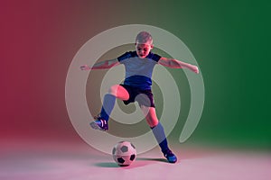 Teen male football or soccer player, boy on gradient background in neon light - motion, action, activity concept