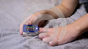 Teen Measures Pulse and Oxygen Saturation Using a Pulse Oximeter in Bedroom