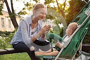 Teen nanny with  baby in stroller playing in park