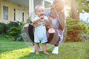 Teen nanny with cute baby on green grass