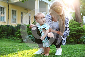 Teen nanny with cute baby on green grass