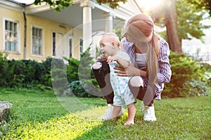Teen nanny with cute baby on green grass. Space for text