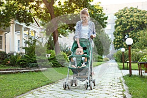 Teen nanny with cute baby in stroller walking. Space for text