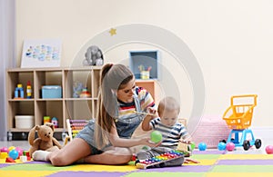 Teen nanny and cute little baby playing with toys