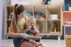 Teen nanny and cute little baby playing with toys