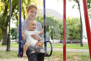 Teen nanny with cute little baby on swing. Space for text