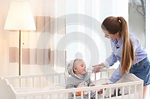 Teen nanny giving cute little baby water from bottle