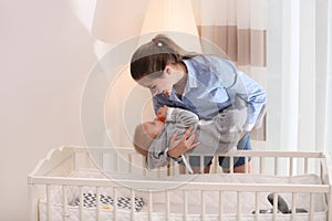 Teen nanny putting cute little baby in crib. Daytime sleep