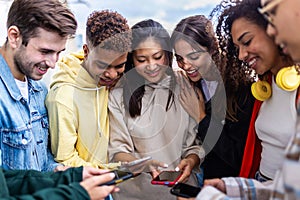 Teen people using cell phone together outdoors