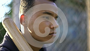 Teen player holding baseball bat, waiting for game, street sport, mental warm-up