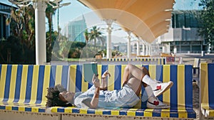 Teen reader enjoy literature lying on campus bench sunny day. Girl reading book