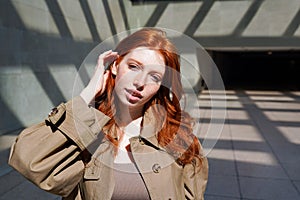 Teen redhead girl looking at camera standing among urban walls.