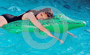 Teen relax in luxury swimming pool. Fashion crocodile leather and girl in water. Summer vacation and travel to ocean