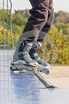 Teen with roller skates performing a stunt on a half pipe ramp.