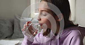 Teen school girl drinking fresh mineral water at home, closeup