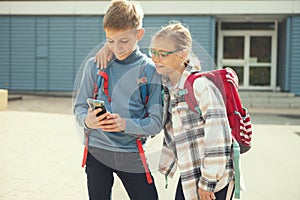 Teen schoolchildren playing with cell phone in school yard