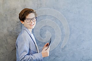 Teen schooler boy in eyeglasses holds tablet