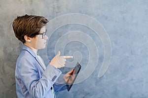 Teen schooler boy in eyeglasses holds tablet PC