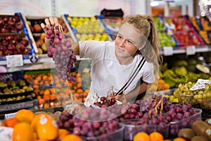 Teen shopper chooses grape at grocery store