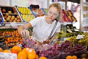 Teen shopper chooses grape at grocery store