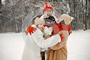 Teen siblings, their mother and black dog standing at winter park