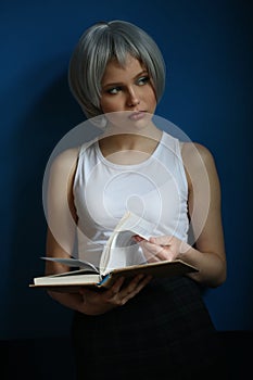 Teen with silver hair leafing through the book. Close up. Blue background