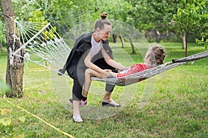 Teen sister girls and child having fun on hammock in the backyard garden