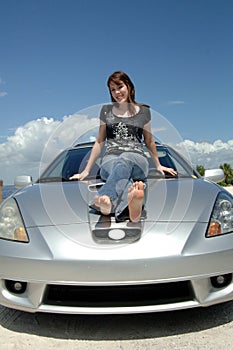 Teen sitting on car hood