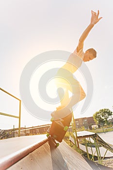 Teen skater hang up over a ramp on a skateboard in a skate park