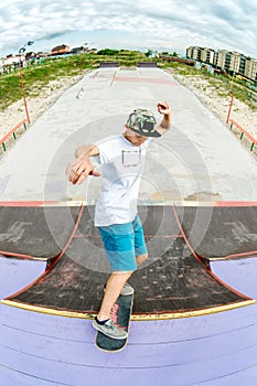 Teen skater hang up over a ramp on a skateboard in a skate park