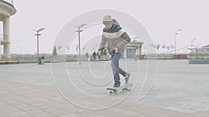 Teen skater practicing shuvit trick in city square