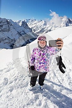 Teen ski girl do selfie with phone over mountain