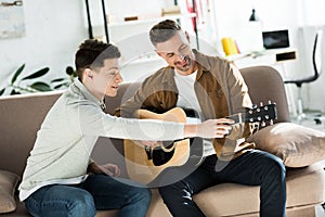 Teen son teaching father play acoustic guitar photo