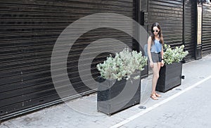 Teen standing in front of black store and planters