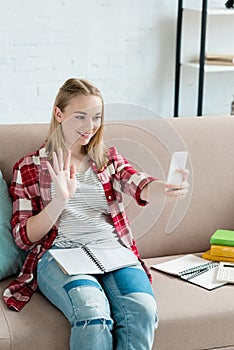 teen student girl making video call with smartphone and waving