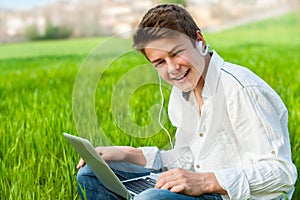 Teen student with laptop outdoors.