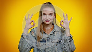 Teen stylish girl looking approvingly at camera showing ok gesture like sign positive something good