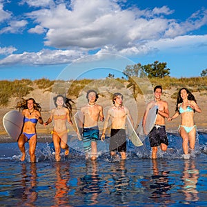 Teen surfers group running beach splashing