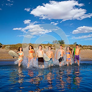 Teen surfers group running beach splashing