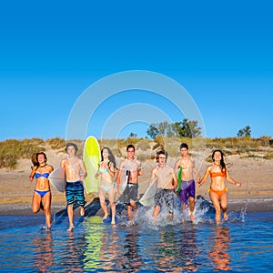 Teen surfers group running beach splashing