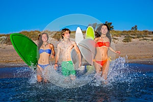 Teen surfers group running beach splashing