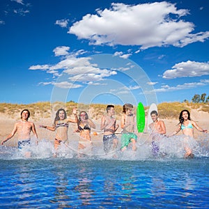 Teen surfers group running beach splashing