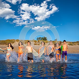 Teen surfers group running beach splashing