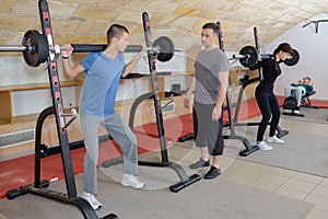 Teen training with weights at gym club with coach