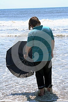 Teen With Umbrella Facing The Ocean