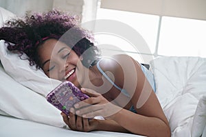 Teen Using Mobile Telephone For Chat In Bed At Home