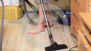 Teen vacuums floor using vacuum cleaner in room bottom view