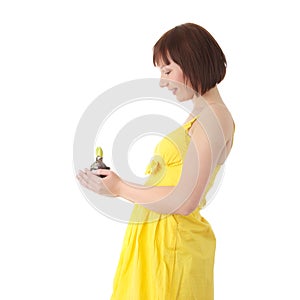 Teen woman in yellow dress holding small plant